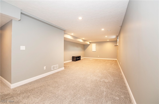 basement with a textured ceiling and light carpet