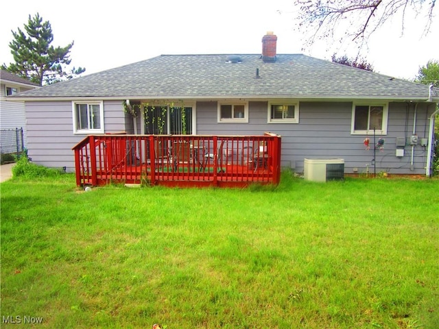 back of property with a shingled roof, a yard, and a chimney