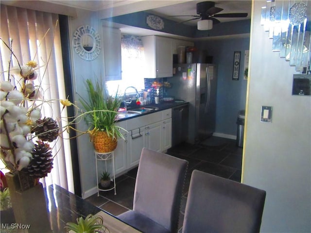 kitchen with dark countertops, white cabinets, a sink, dishwasher, and dark tile patterned floors