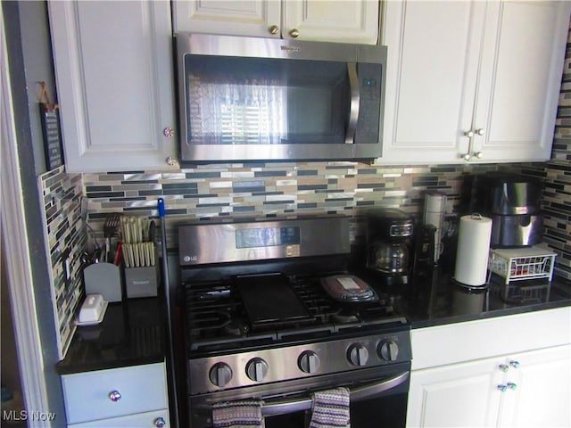 kitchen featuring appliances with stainless steel finishes, dark countertops, white cabinets, and backsplash