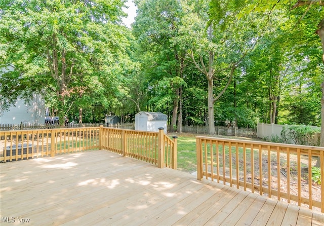 wooden terrace featuring a storage unit and a lawn