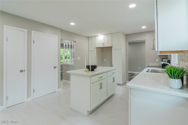 kitchen with light tile patterned flooring, sink, a kitchen island, and white cabinets