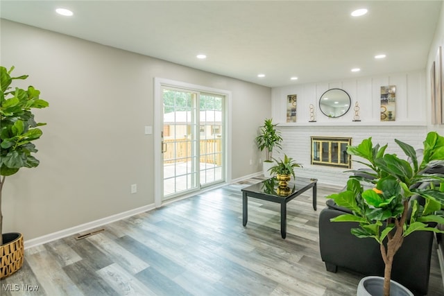 living area with light hardwood / wood-style flooring and a brick fireplace