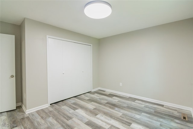 unfurnished bedroom featuring a closet and light hardwood / wood-style floors