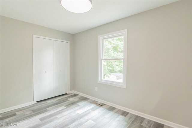 unfurnished bedroom featuring light wood-type flooring and a closet