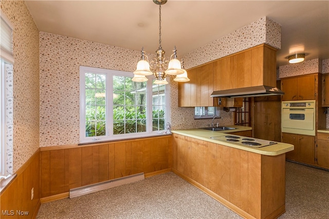 kitchen with sink, a notable chandelier, a baseboard radiator, white appliances, and kitchen peninsula