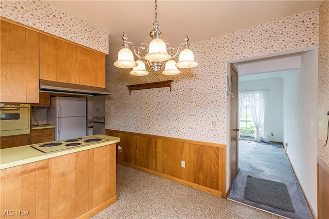 kitchen featuring white appliances, a notable chandelier, light carpet, and hanging light fixtures