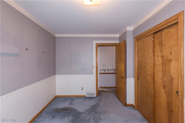 unfurnished bedroom with carpet, a closet, and ornamental molding