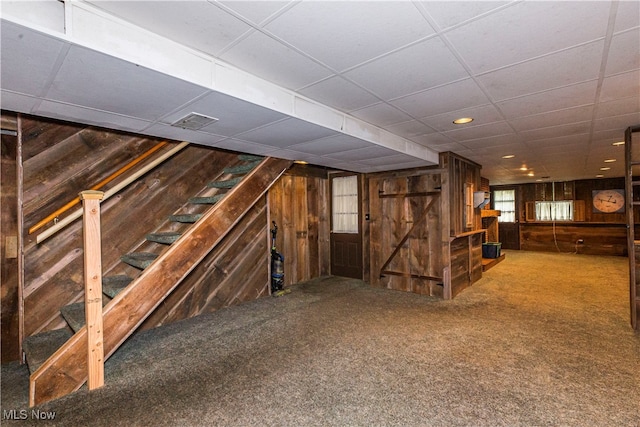 interior space with wood walls, a paneled ceiling, and carpet