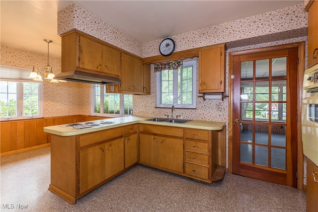 kitchen with sink, a chandelier, stainless steel gas stovetop, kitchen peninsula, and pendant lighting