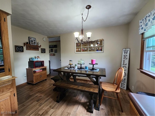 dining space with dark wood-type flooring and a notable chandelier