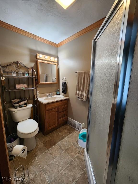 bathroom featuring a shower with door, ornamental molding, vanity, and toilet