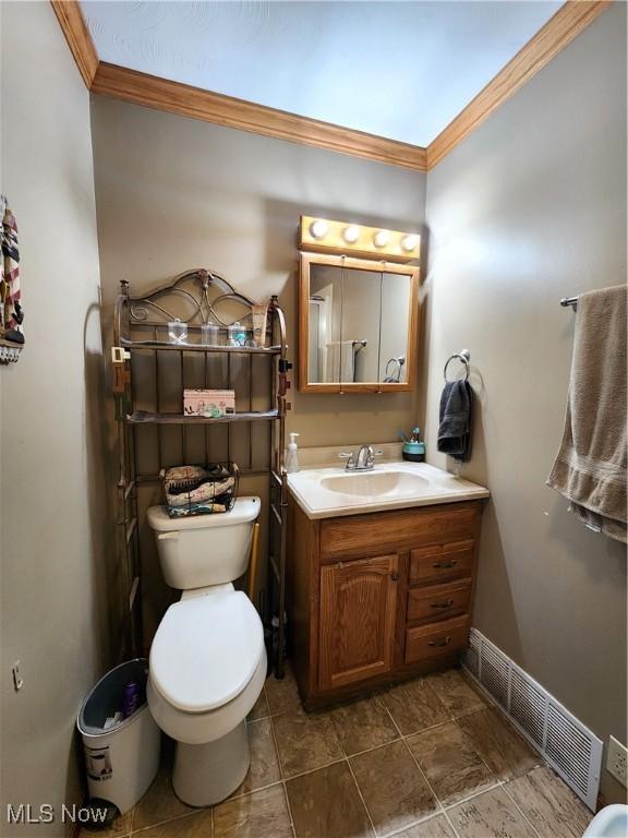 bathroom with ornamental molding, vanity, and toilet