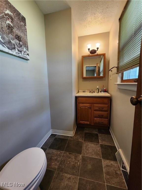 bathroom featuring vanity, a textured ceiling, and toilet