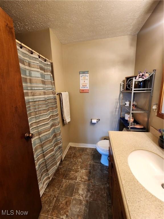 bathroom featuring vanity, toilet, and a textured ceiling