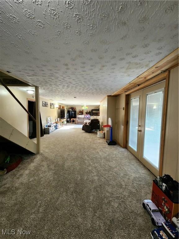 interior space with carpet floors, french doors, and a textured ceiling