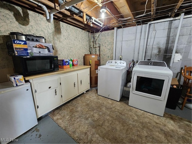 laundry room with cabinets, washing machine and clothes dryer, and water heater