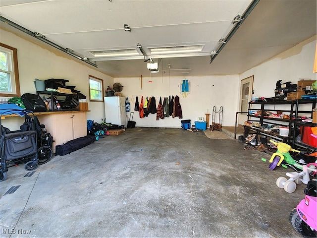 garage with a garage door opener and white refrigerator