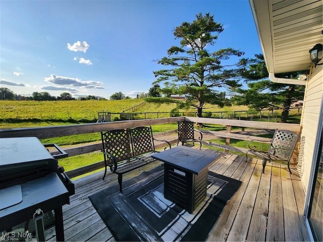 wooden deck with a rural view and a grill