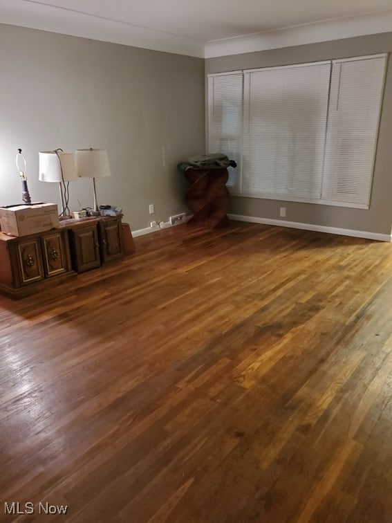 interior space with dark wood-style flooring, baseboards, and ornamental molding