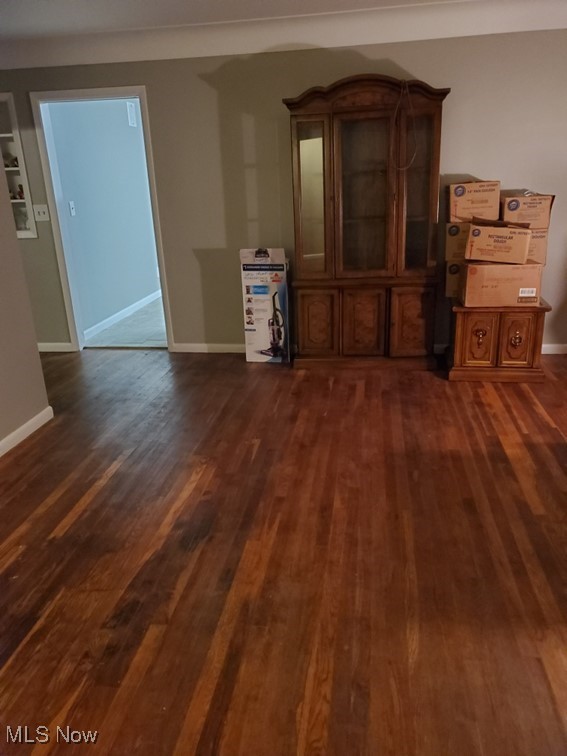 unfurnished living room featuring dark wood-style flooring and baseboards