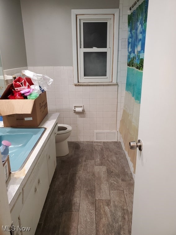 full bath with visible vents, toilet, tile walls, vanity, and curtained shower