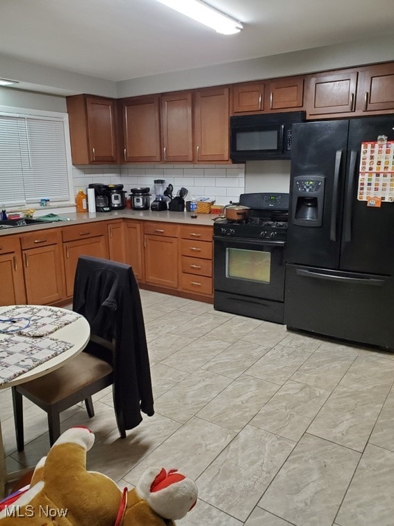 kitchen with light countertops, brown cabinets, decorative backsplash, and black appliances