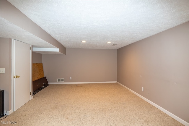 basement featuring light carpet and a textured ceiling