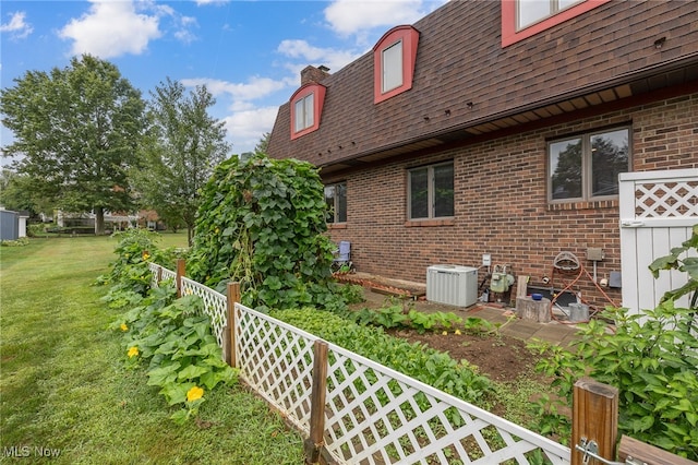 view of side of property featuring central AC unit and a lawn