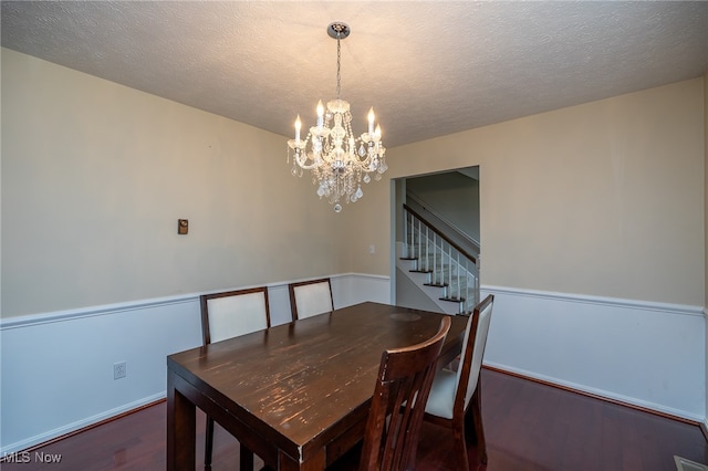 dining space with a textured ceiling, a chandelier, and dark hardwood / wood-style flooring