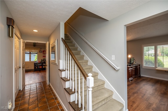 stairs featuring a textured ceiling and hardwood / wood-style floors