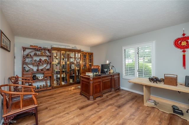 office space featuring light wood-type flooring and a textured ceiling