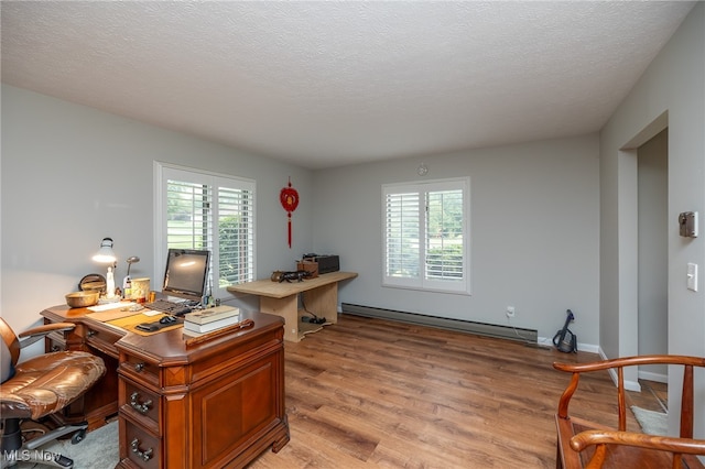 home office with light hardwood / wood-style flooring, a wealth of natural light, a textured ceiling, and a baseboard radiator