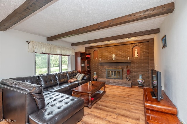 living room featuring a textured ceiling, light hardwood / wood-style floors, a fireplace, and beam ceiling