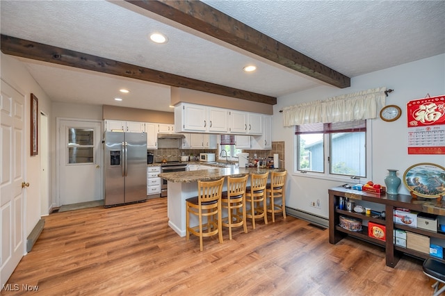 kitchen featuring appliances with stainless steel finishes, light hardwood / wood-style floors, white cabinetry, a kitchen bar, and kitchen peninsula