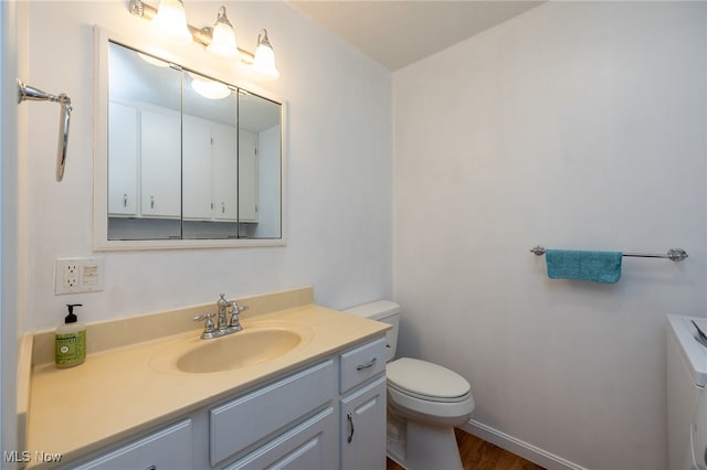 bathroom with toilet, vanity, and hardwood / wood-style floors