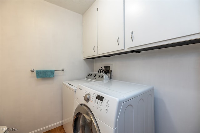 clothes washing area with washing machine and dryer and cabinets