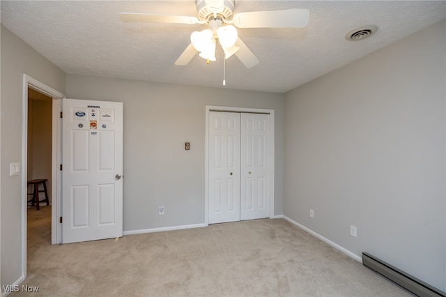 unfurnished bedroom with a closet, a textured ceiling, baseboard heating, ceiling fan, and light colored carpet