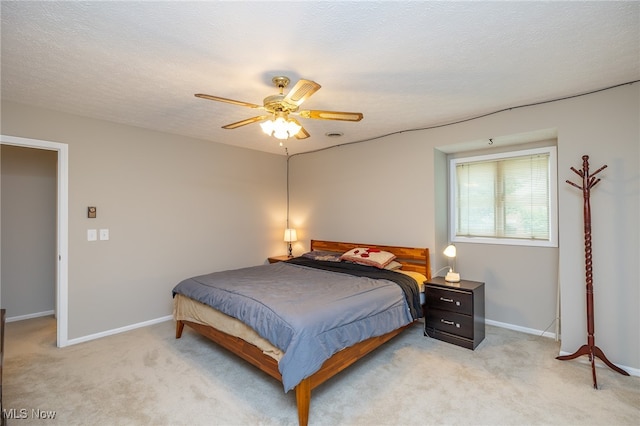 carpeted bedroom with ceiling fan and a textured ceiling