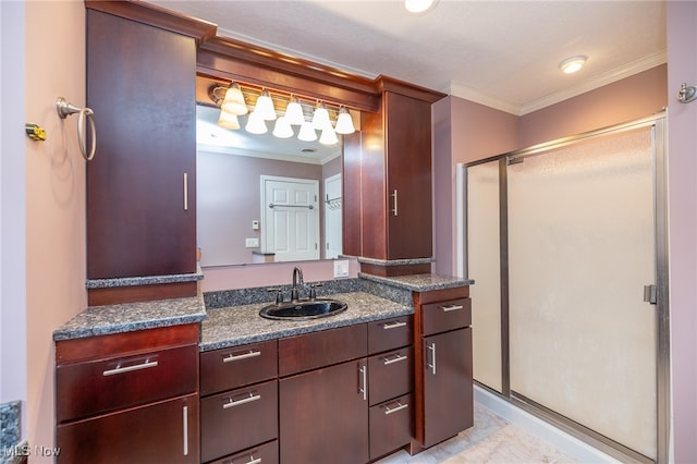 bathroom with a shower with shower door, vanity, and crown molding