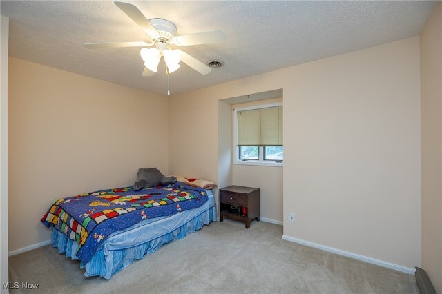 carpeted bedroom featuring ceiling fan and a textured ceiling