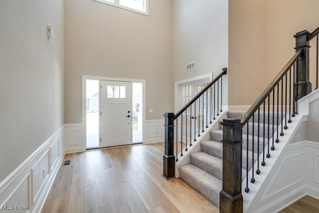 foyer featuring a towering ceiling and light wood-type flooring