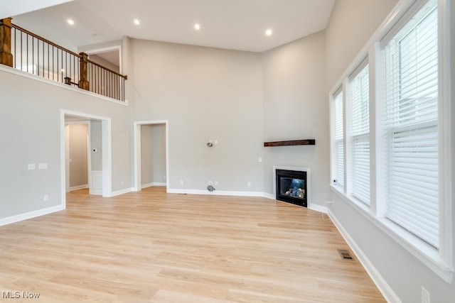 unfurnished living room with light hardwood / wood-style floors and a high ceiling