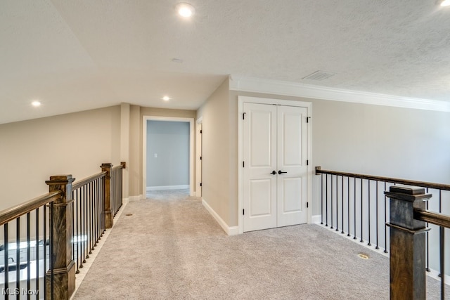 hallway featuring ornamental molding, a textured ceiling, and light carpet