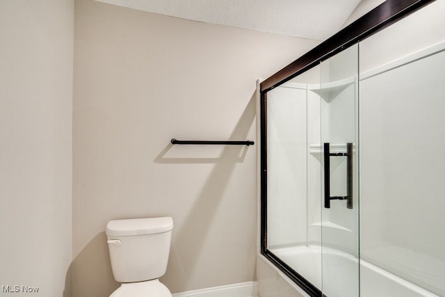 bathroom featuring toilet, a textured ceiling, and enclosed tub / shower combo