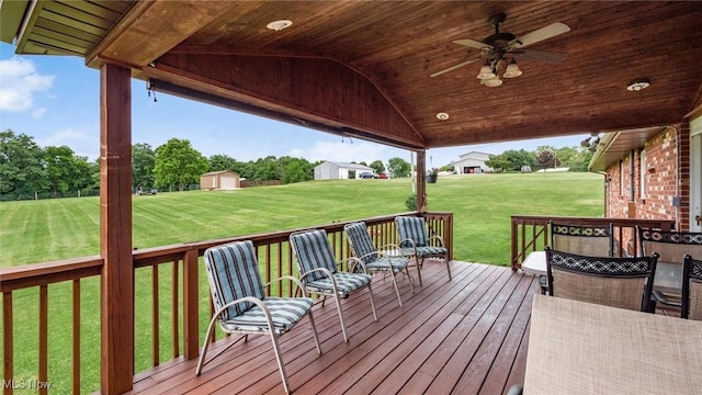 wooden deck featuring a lawn, an outdoor structure, a storage shed, and ceiling fan