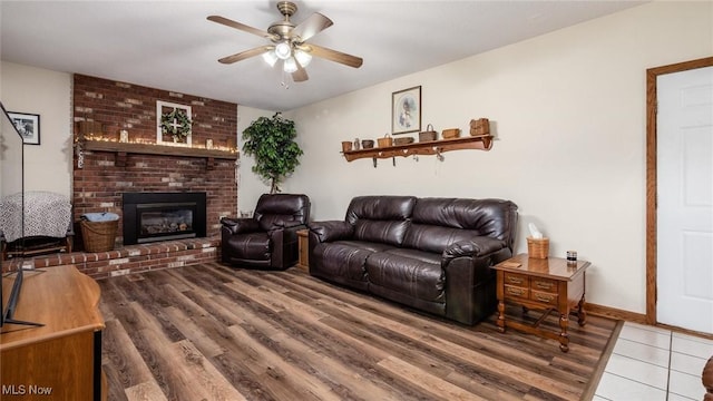 living room featuring a fireplace, wood finished floors, baseboards, and ceiling fan