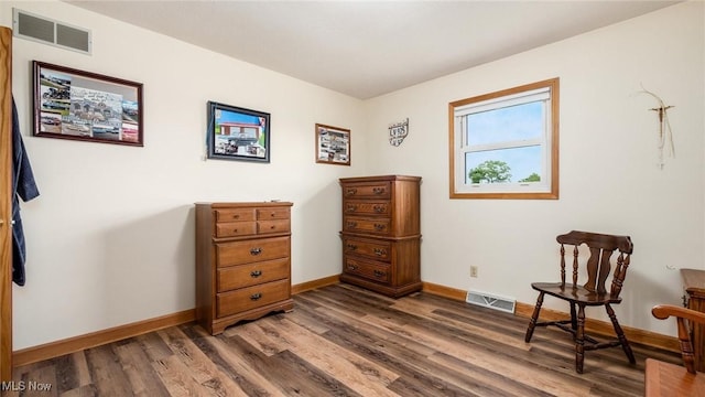 living area with visible vents, baseboards, and wood finished floors