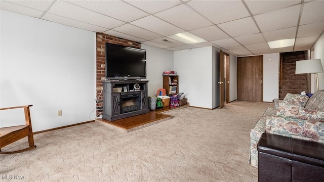 living area with carpet flooring, a fireplace, baseboards, and a drop ceiling