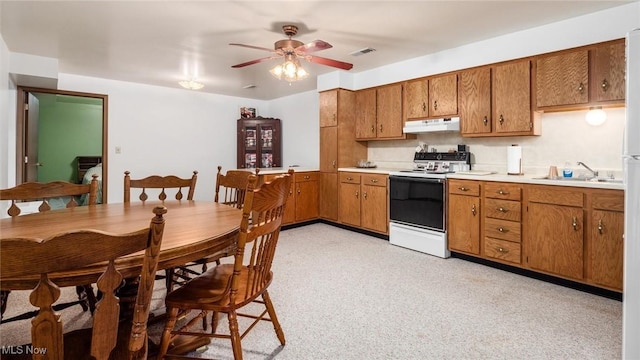 kitchen with electric range, visible vents, under cabinet range hood, a sink, and brown cabinetry